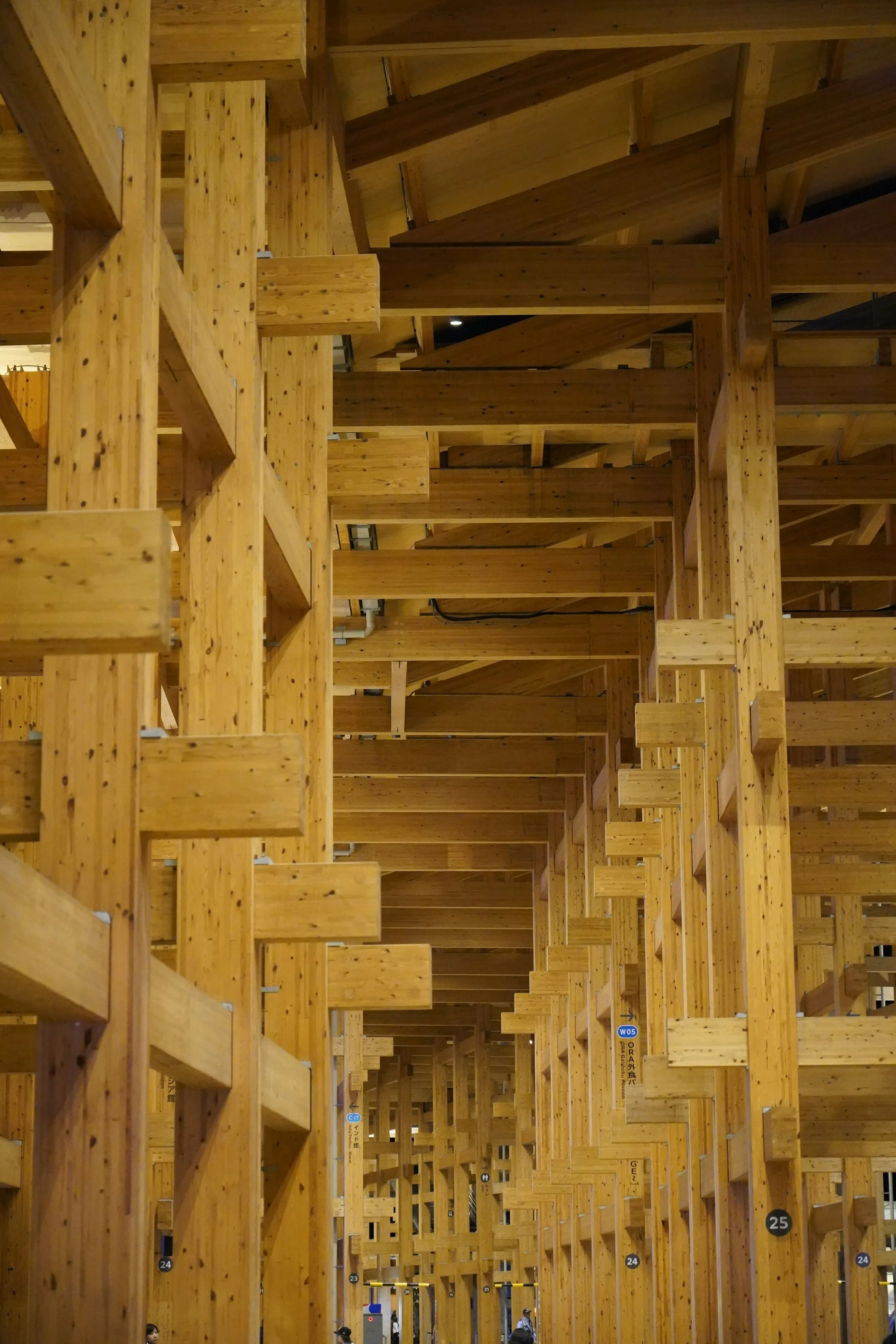 Engineered timber columns and stacked beams receding in dramatic perspective inside a mass-timber tower